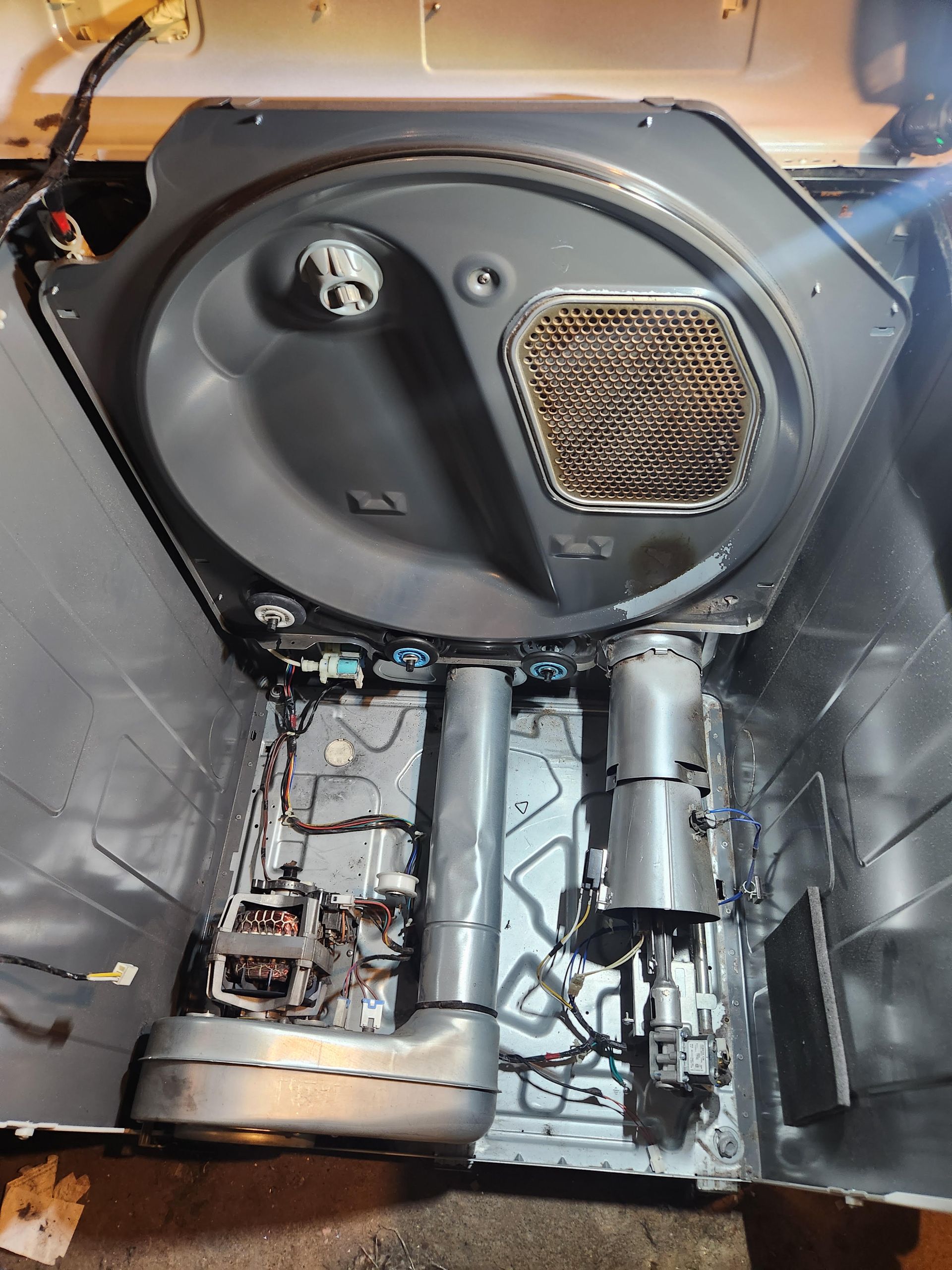 Interior of a vehicle stripped for repair, showing exposed floor panels, wiring, and a black door panel with speaker grille