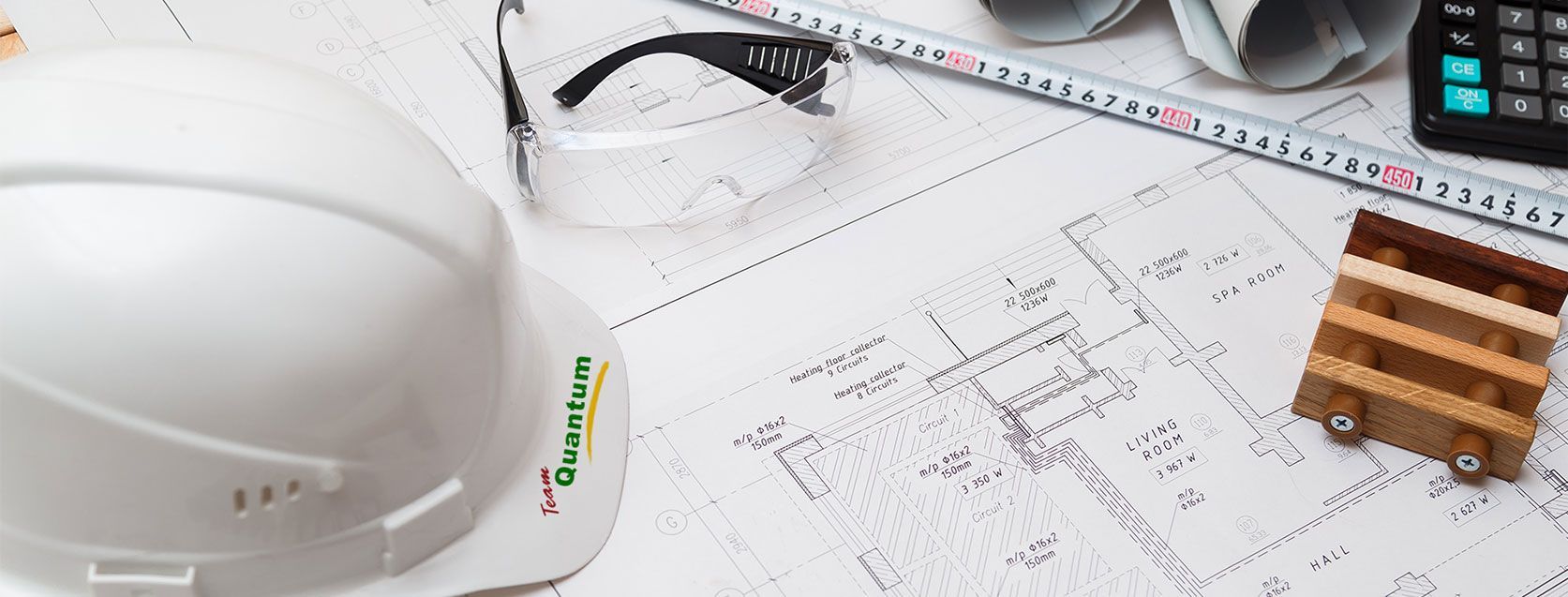 White hard hat on construction blueprints with a phone and wooden blocks on a desk
