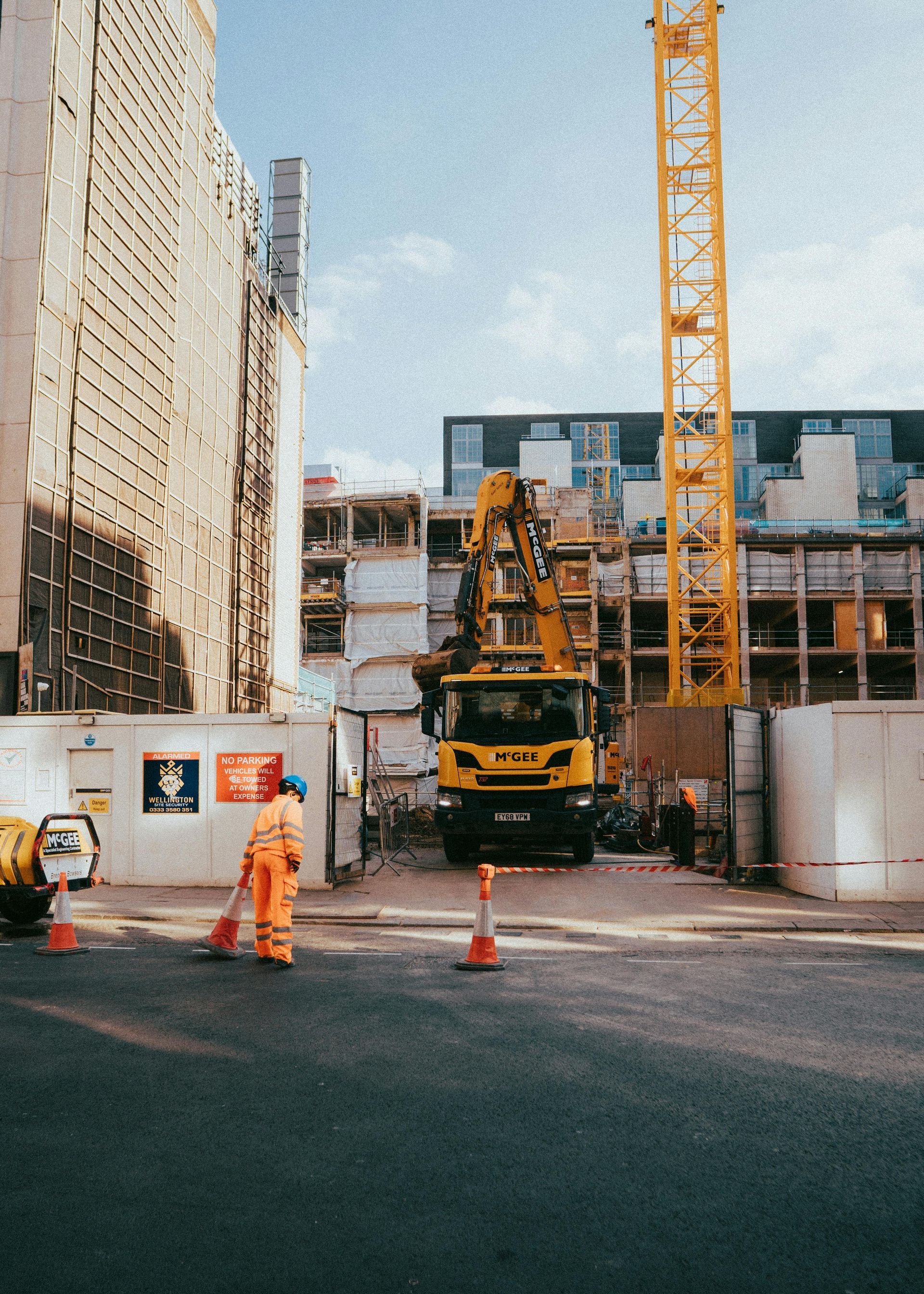 Construction site with yellow crane and workers between concrete buildings