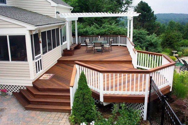 A large wooden deck with stairs and a white railing