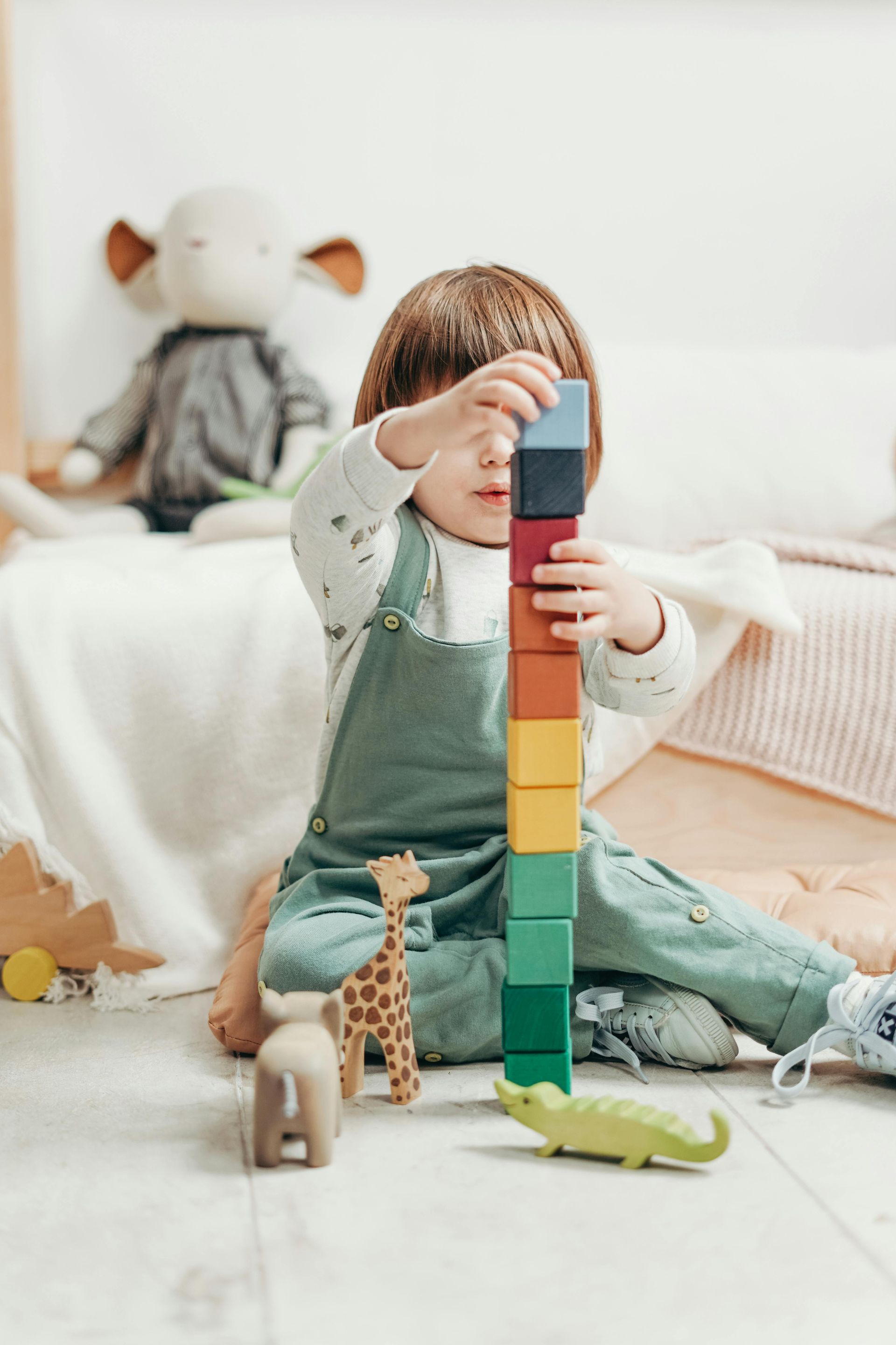 A little girl is sitting on the floor playing with wooden blocks.