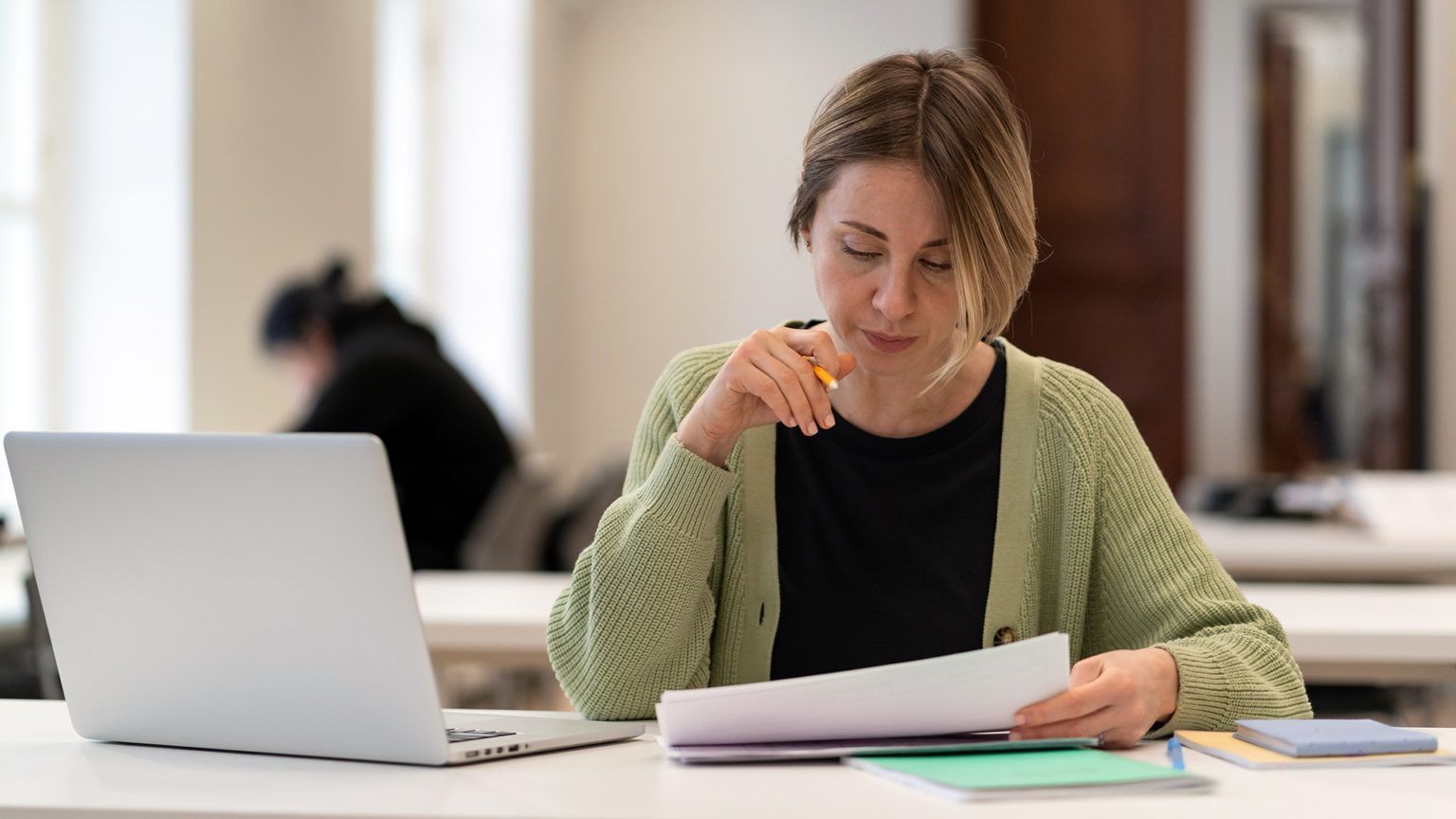 Profissional analisando documentos no escritório com notebook, representando decisão entre suporte