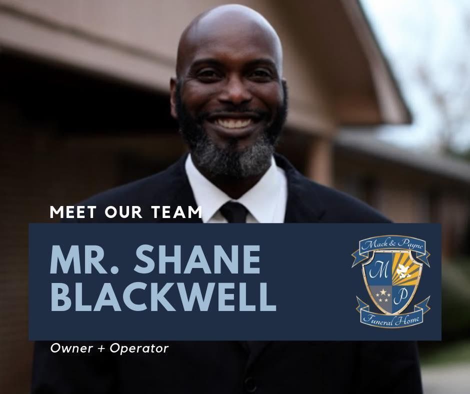 Mr. Shane Blackwell, owner/operator, smiles in a black suit. Dark hair, beard. Background: building, logo.