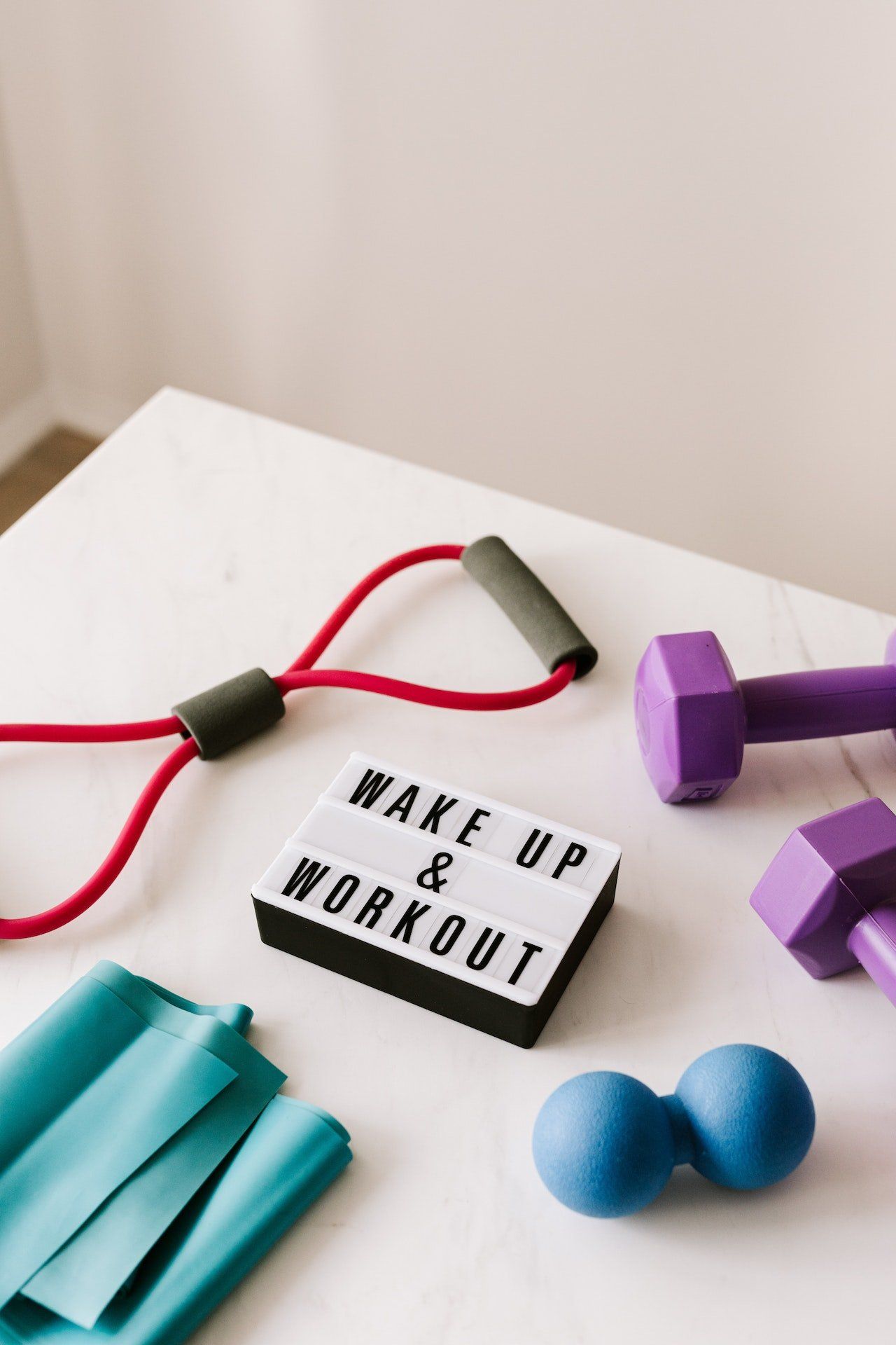 A white table topped with exercise equipment and a sign that says wake up and workout.