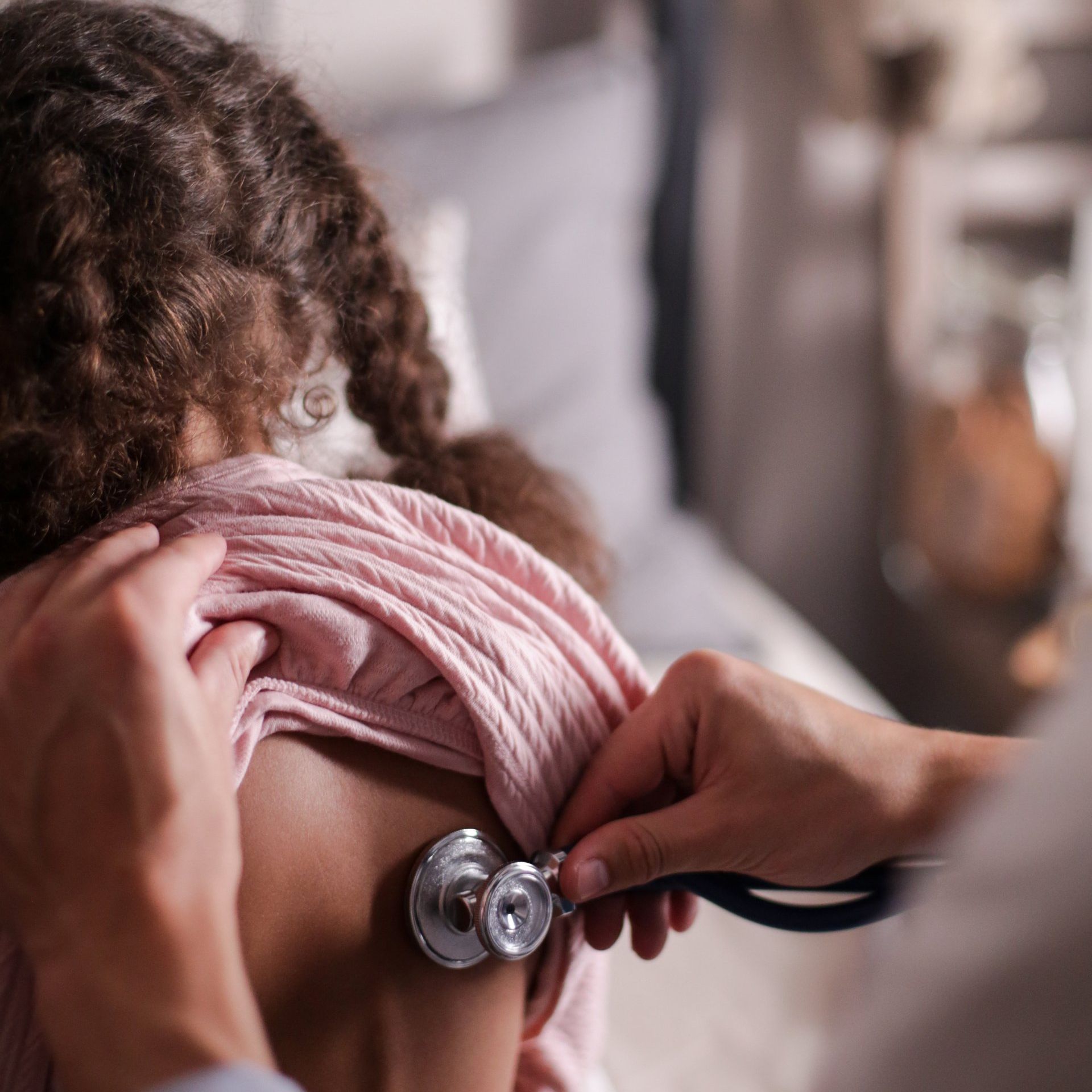 A person is listening to a child 's lungs with a stethoscope.