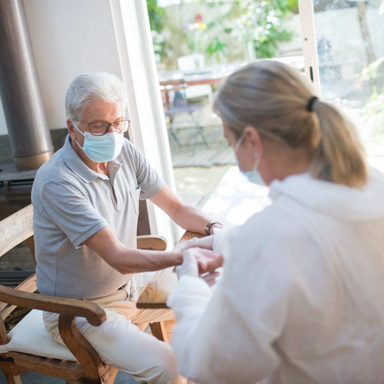 A man wearing a mask is sitting in a chair talking to a woman wearing a mask.