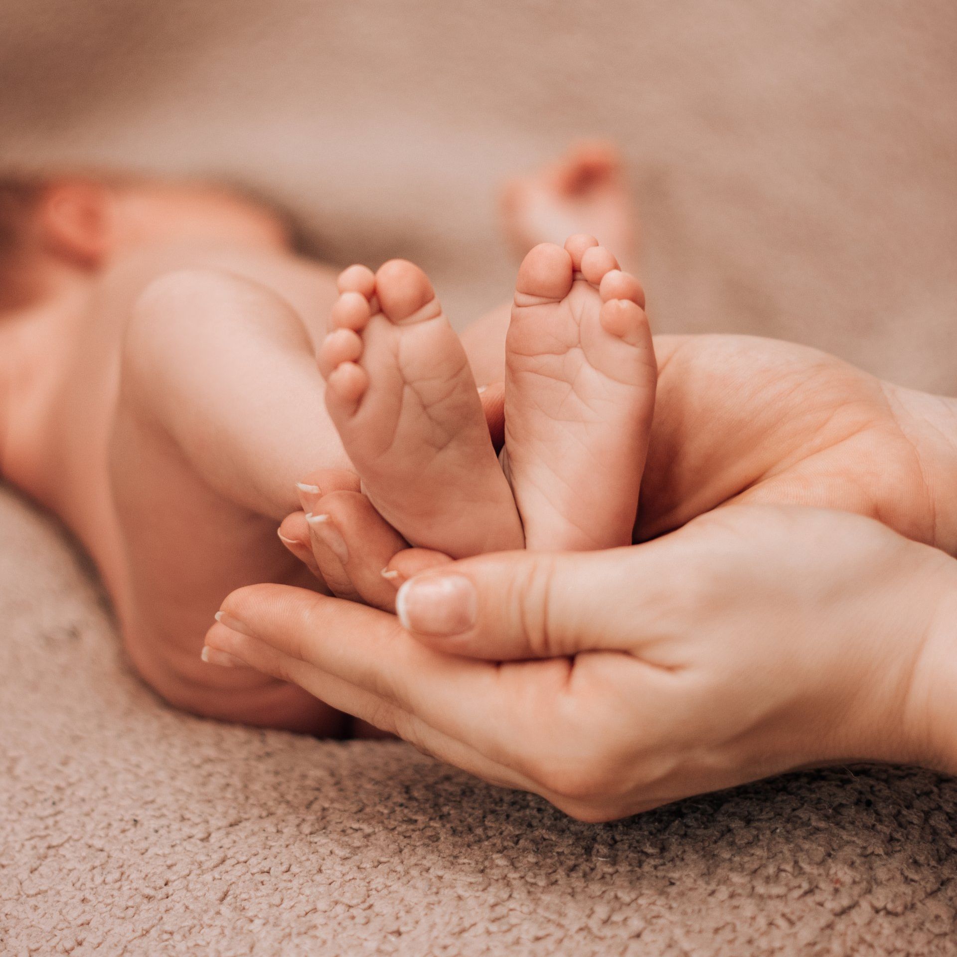 A woman is holding a baby 's feet in her hands.
