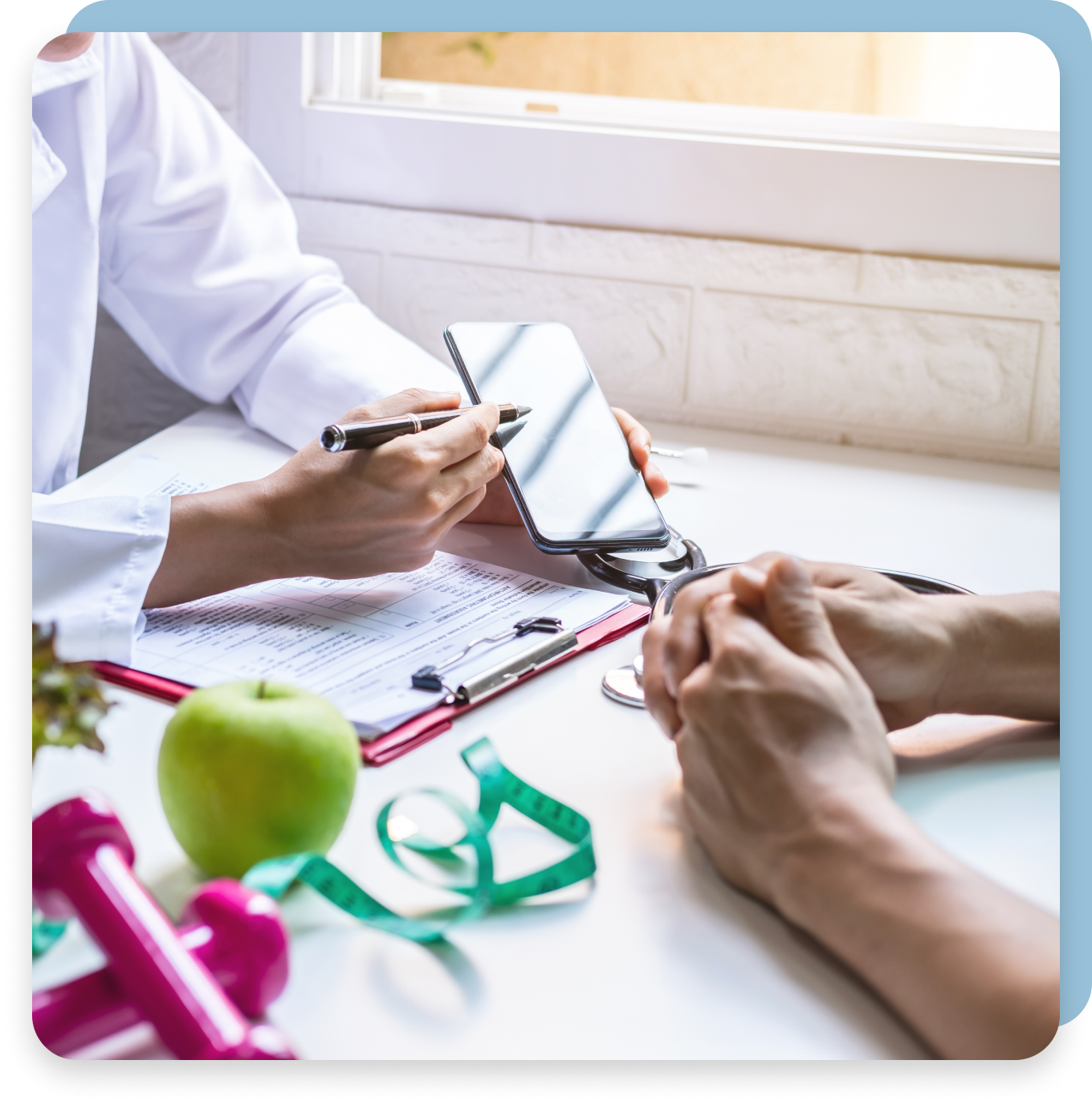 A doctor is talking to a patient while holding a cell phone.