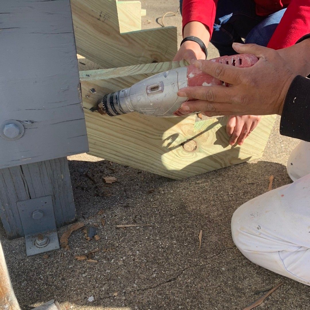 A person is using a drill on a piece of wood.