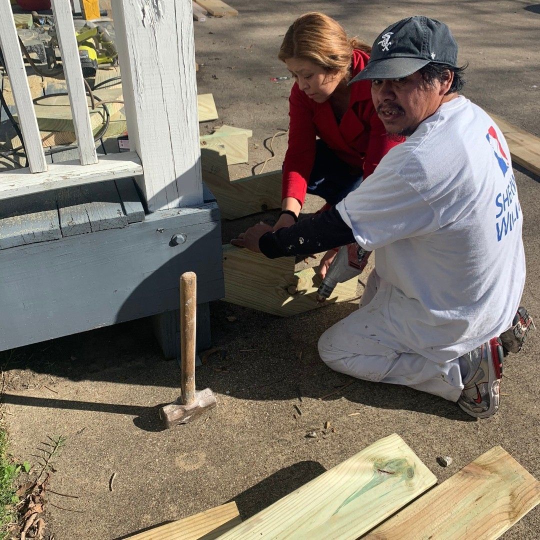 A man and a woman are working on a wooden deck.
