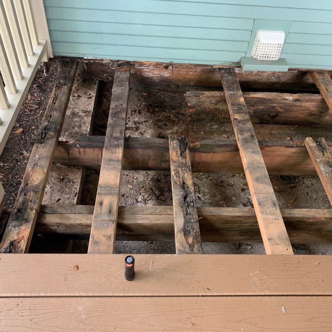 The bottom of a wooden deck with a hole in it.