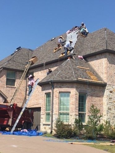 A group of men are working on the roof of a house.
