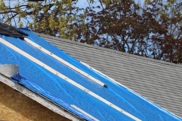 A blue tarp is covering the roof of a house.