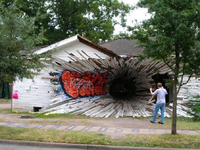 A man standing in front of a house with graffiti on it