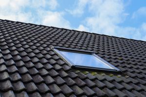 A roof with a skylight on it and a blue sky in the background.