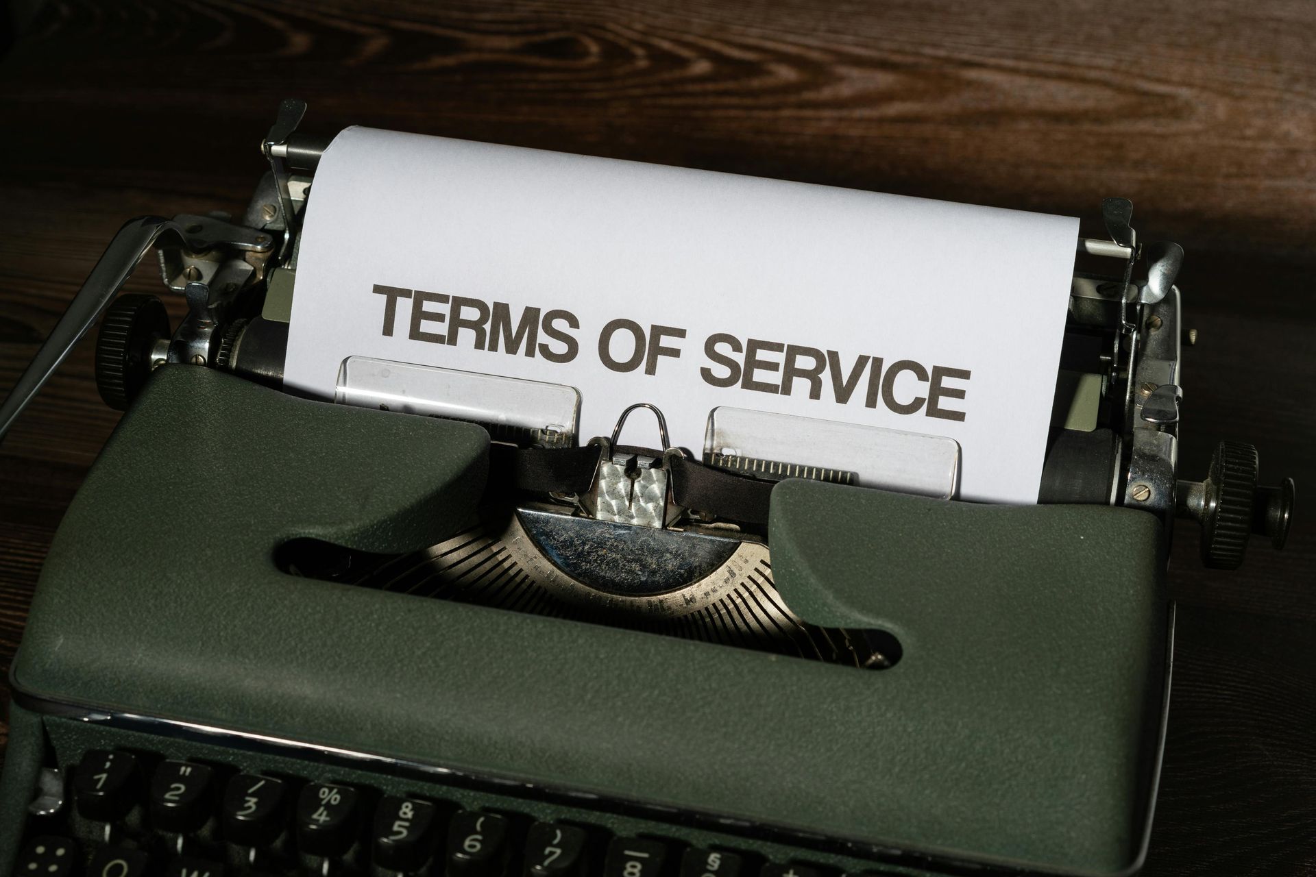 Typewriter with a paper reading “TERMS OF SERVICE” against a dark background