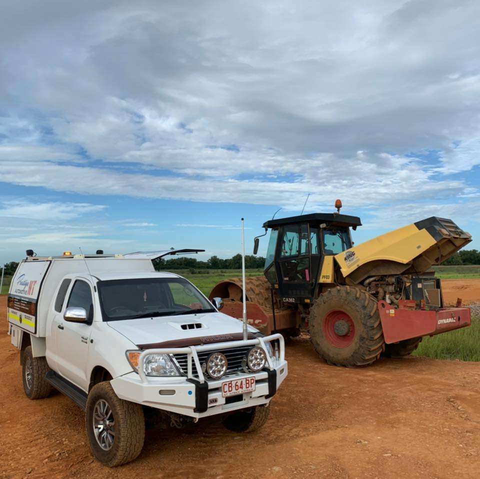 A White Truck Is Parked Next To A Yellow Tractor On A Dirt Road — Prestige Automotive NT In Yarrawonga, NT