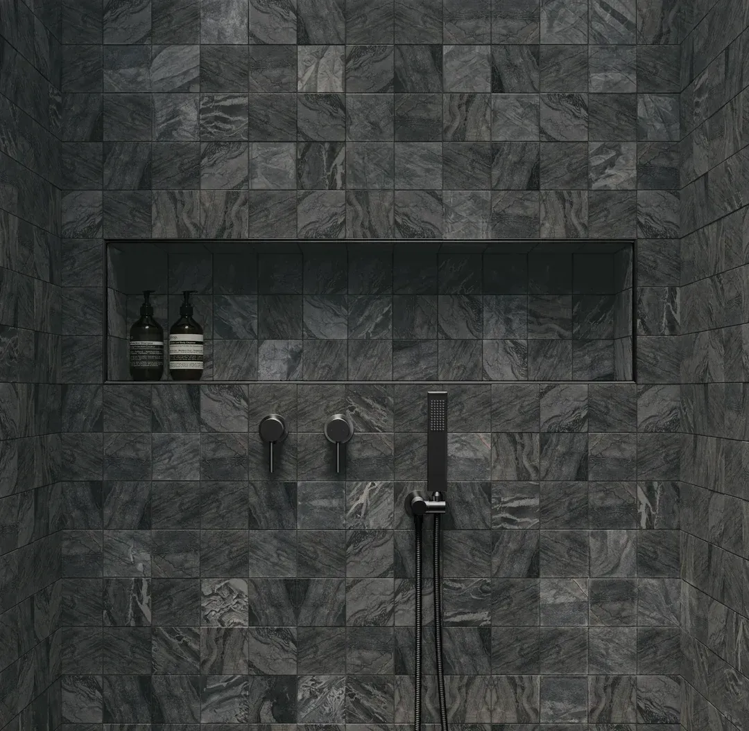 Dark Gray Tiled Shower Wall With Built-in Shelf Holding Two Bottles and a Showerhead Fixture — Stone Arc in Kincumber, NSW