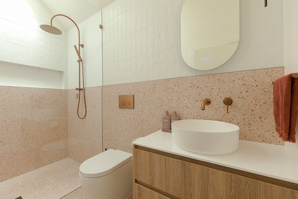 A Bathroom With a Pink Tiled Accent Wall, White Sink, and Wooden Vanity — Stone Arc in Kincumber, NSW