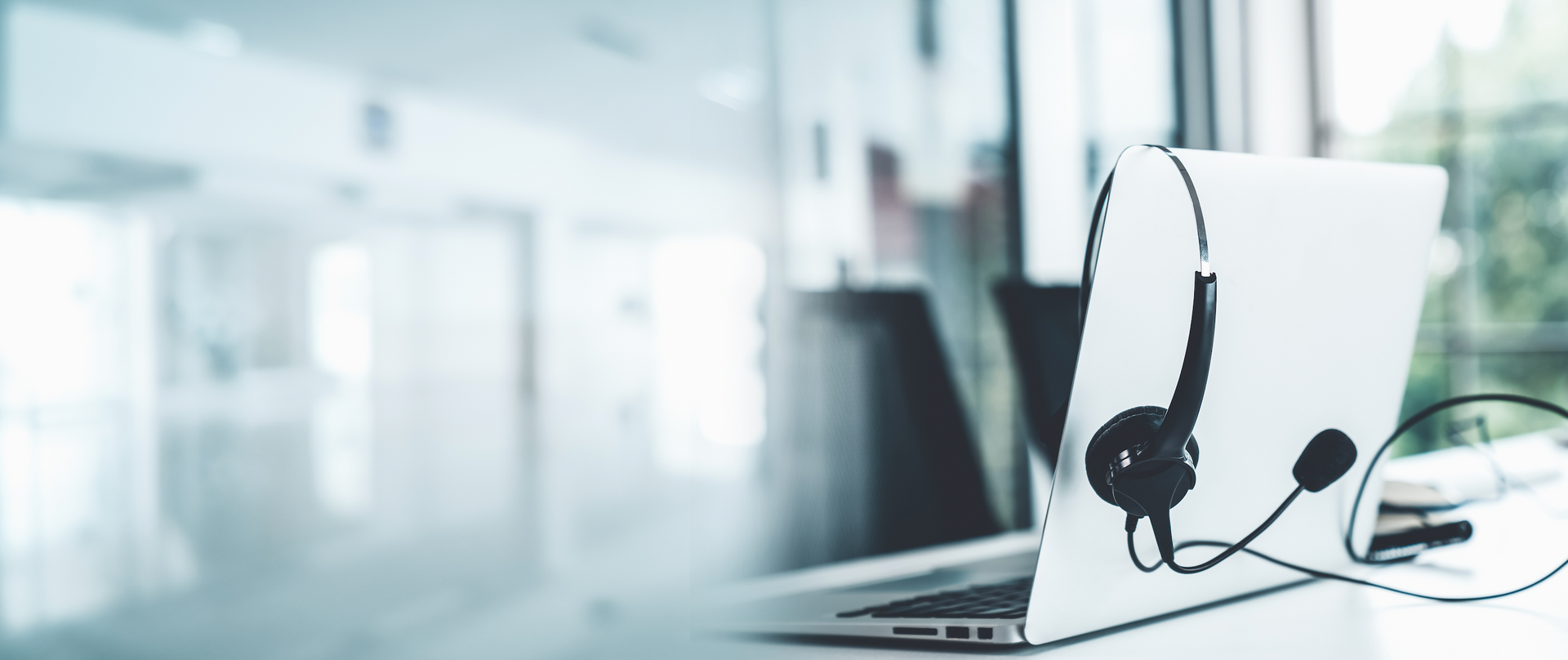 A laptop with a headset attached to it is sitting on a desk.