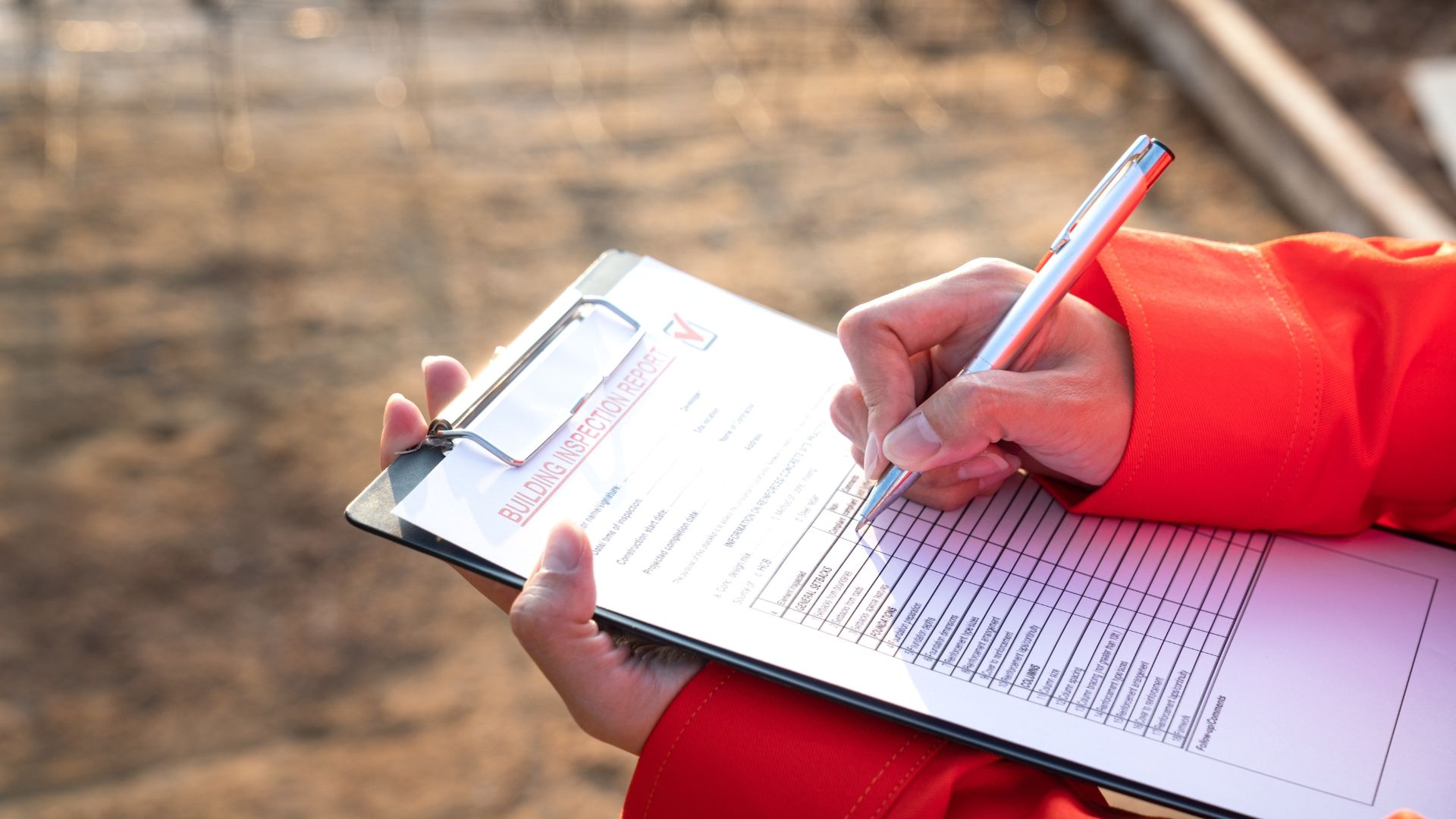 A person is writing on a clipboard with a pen.