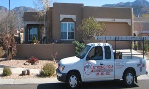 A strong arm truck is parked in front of a house
