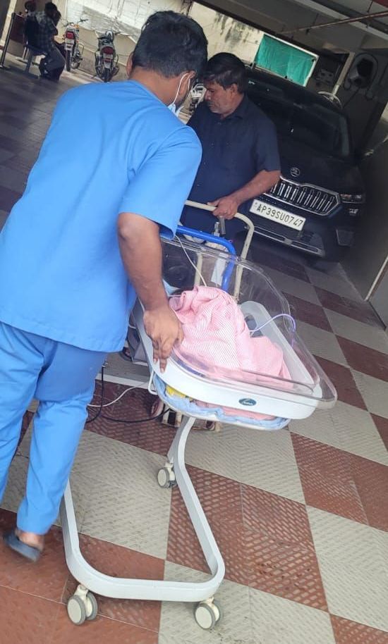 Een verpleegster duwt een brancard met daarin een baby.