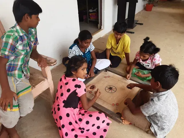 Een groepje kinderen speelt een spelletje op de grond.