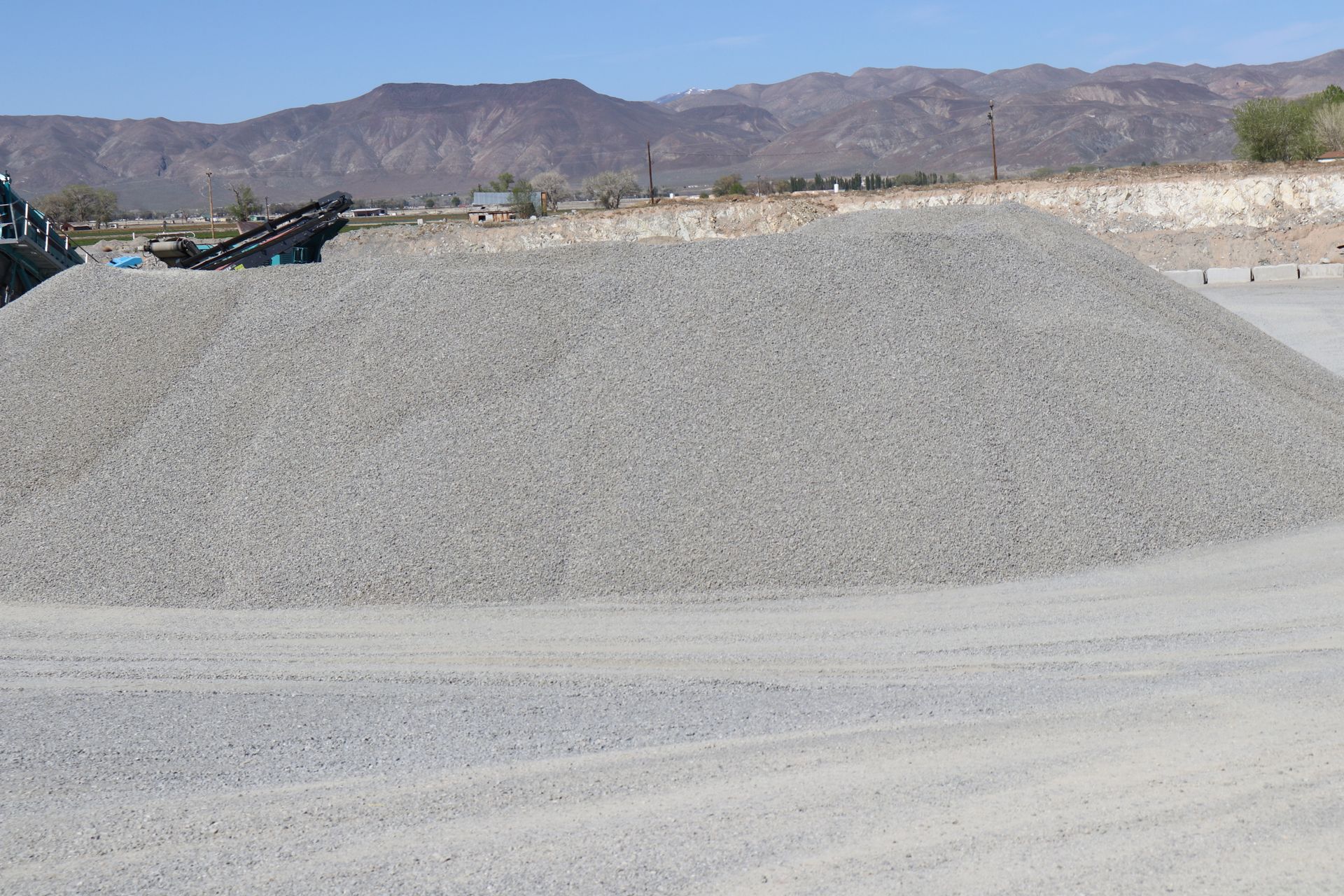 A pile of gravel is sitting on a dirt road with mountains in the background