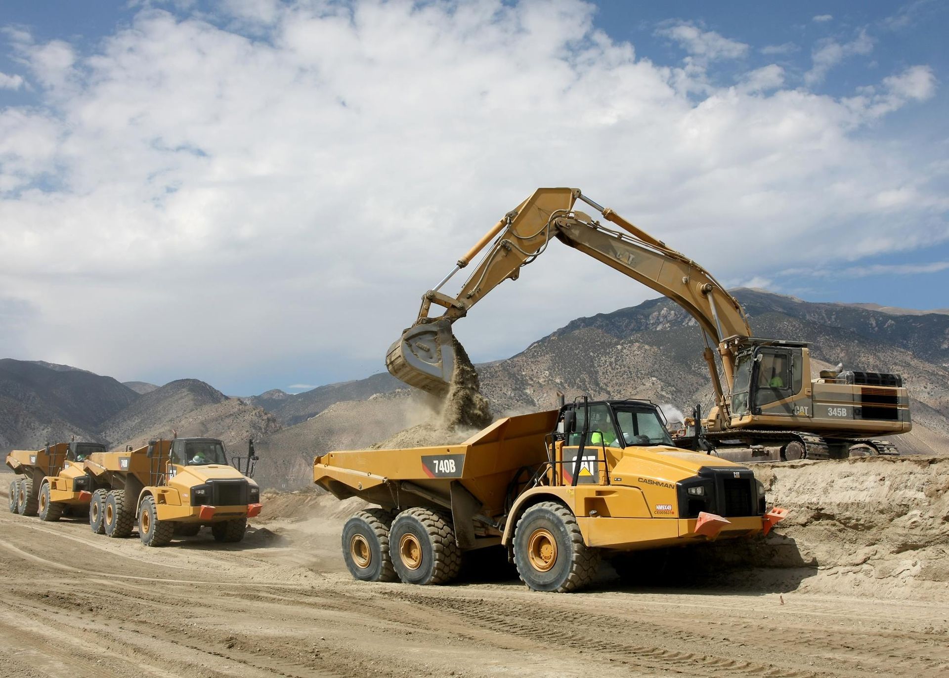 A dump truck is being loaded with dirt by an excavator