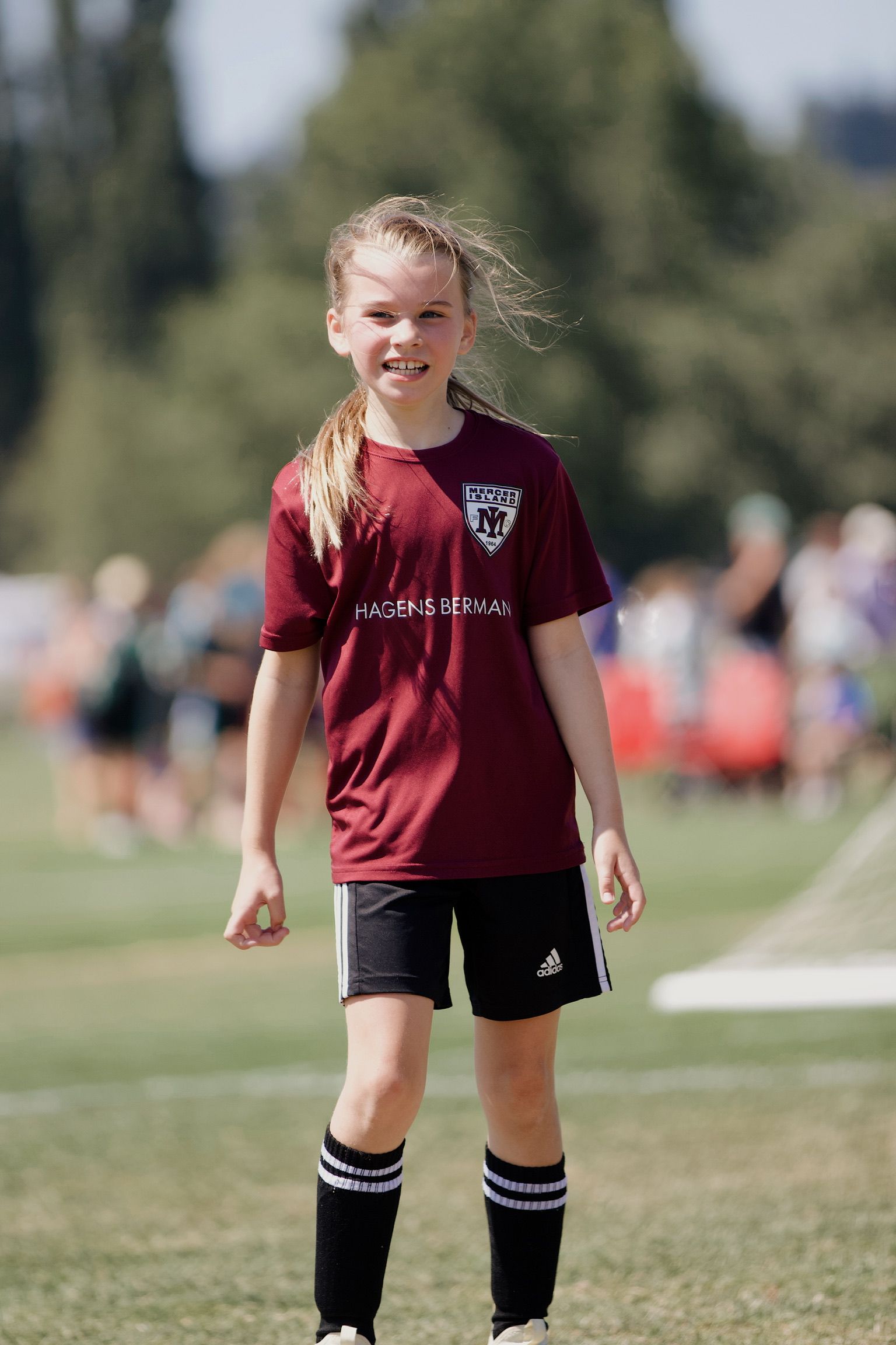 Young soccer player in maroon jersey and black shorts standing on a grassy field