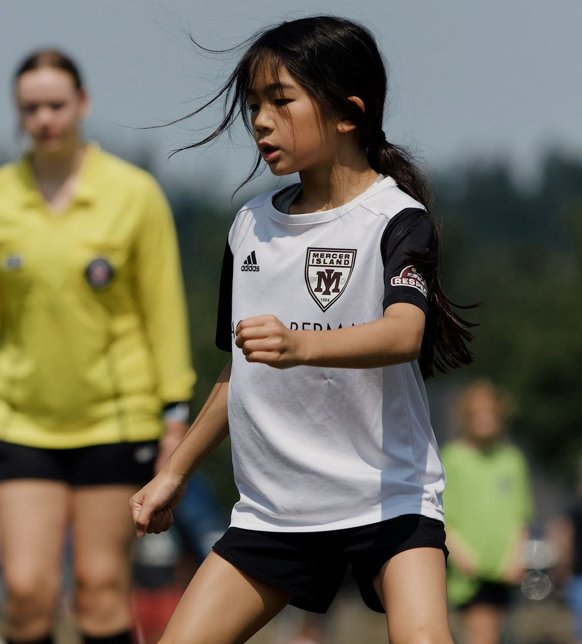 Young soccer player in white jersey and black shorts running on a field