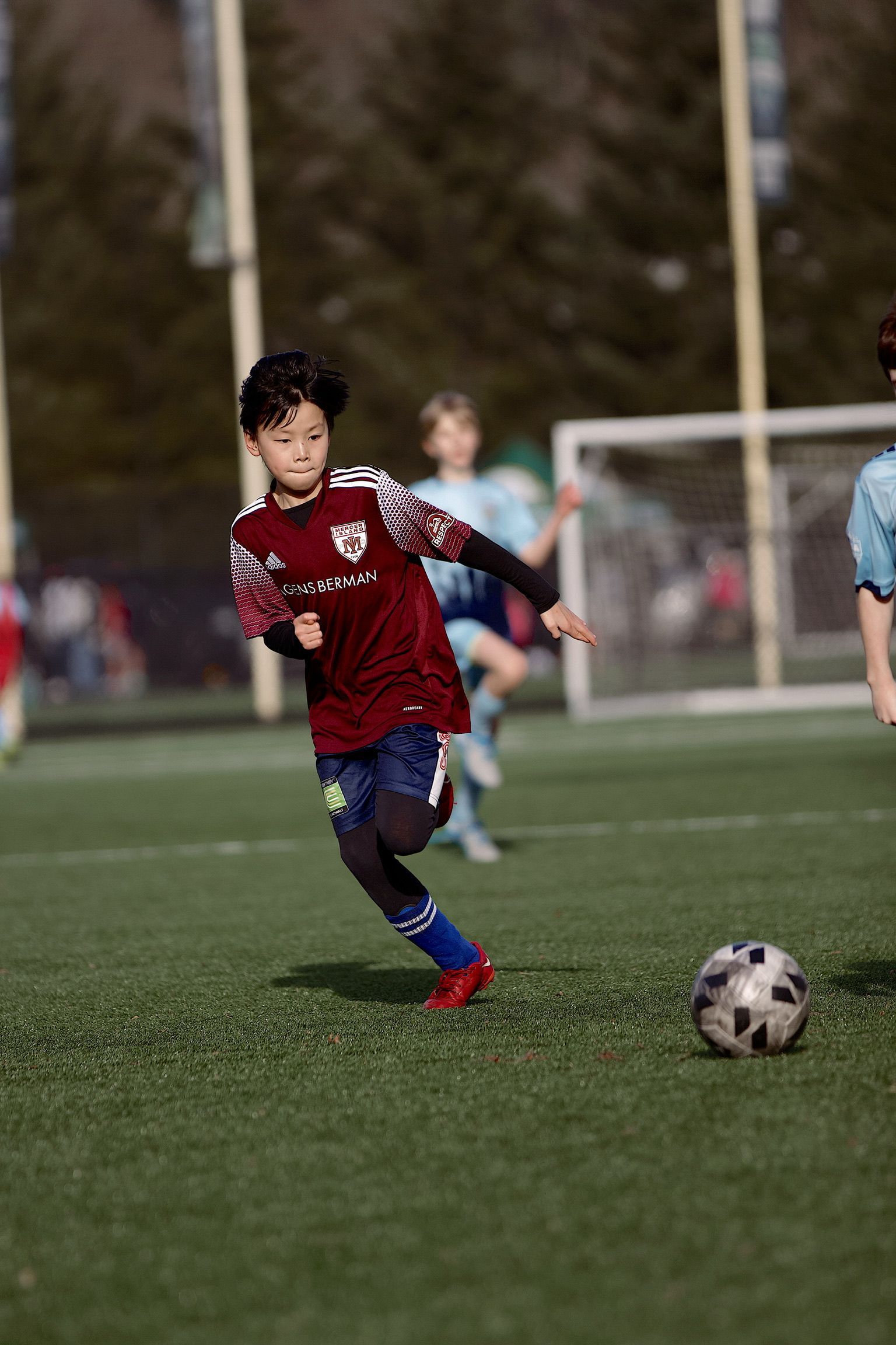 Soccer player in red jersey dribbles on a field toward a ball near the goal
