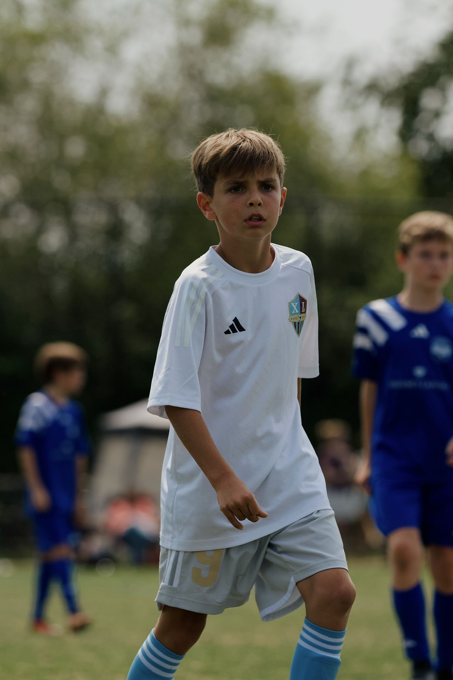 Young soccer player in white uniform standing on a grassy field during a match