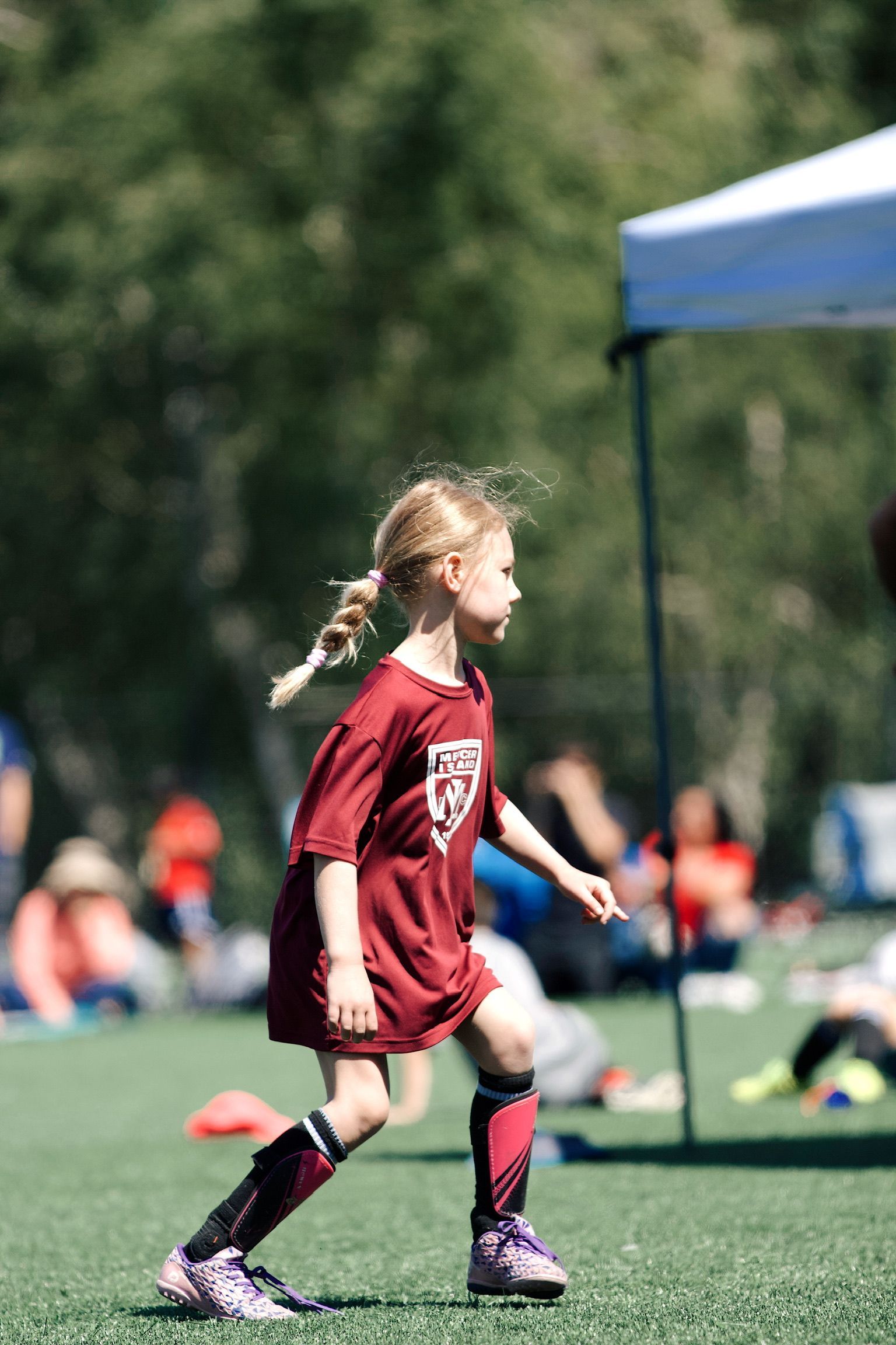 Child in a red soccer jersey running on a field during a game