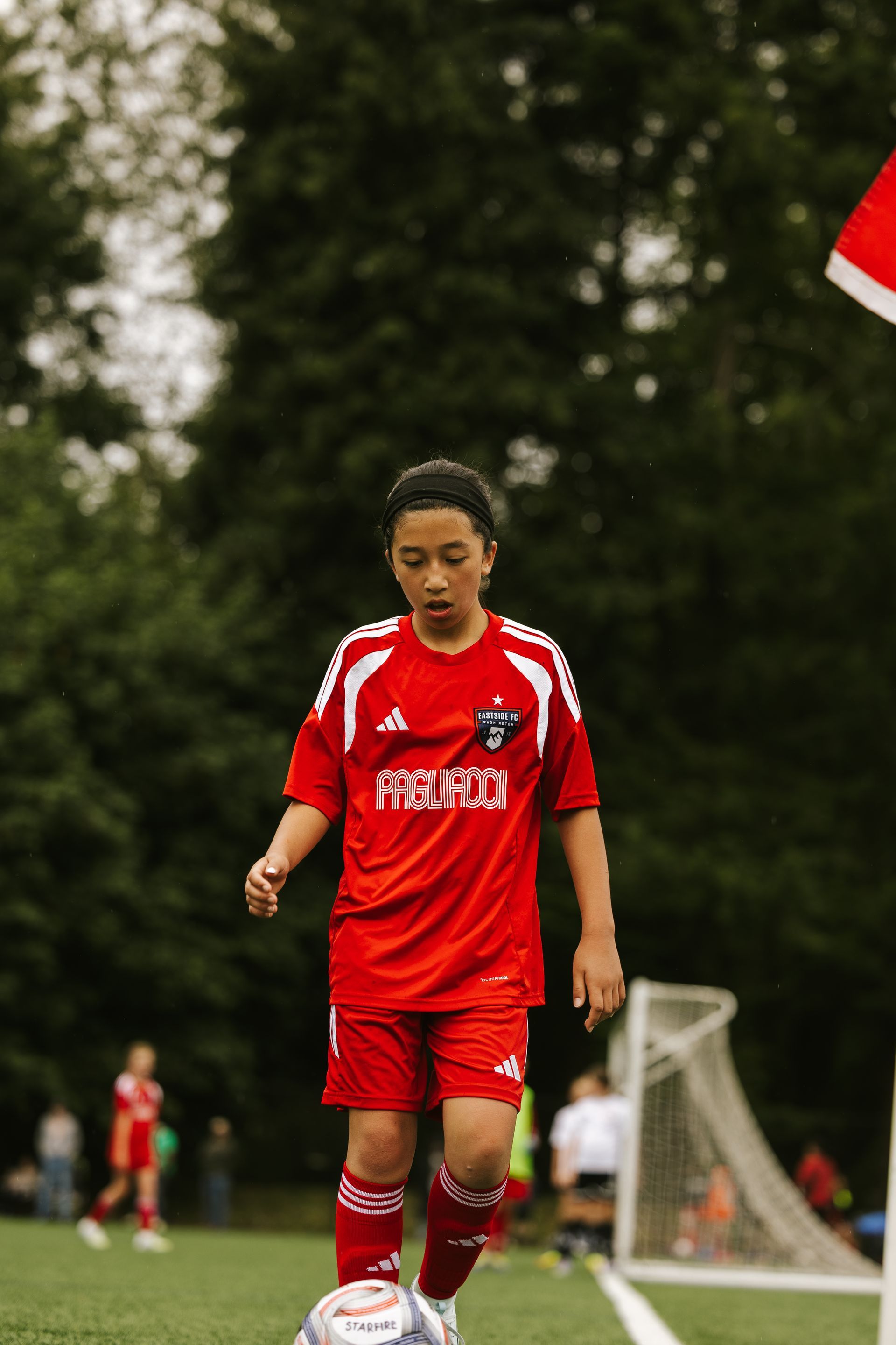 One soccer player in red jersey takes the ball to the corner flag