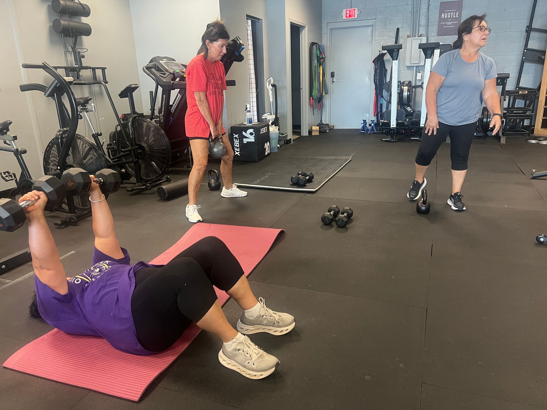 Athlete lifting a barbell overhead in a gym while others train nearby