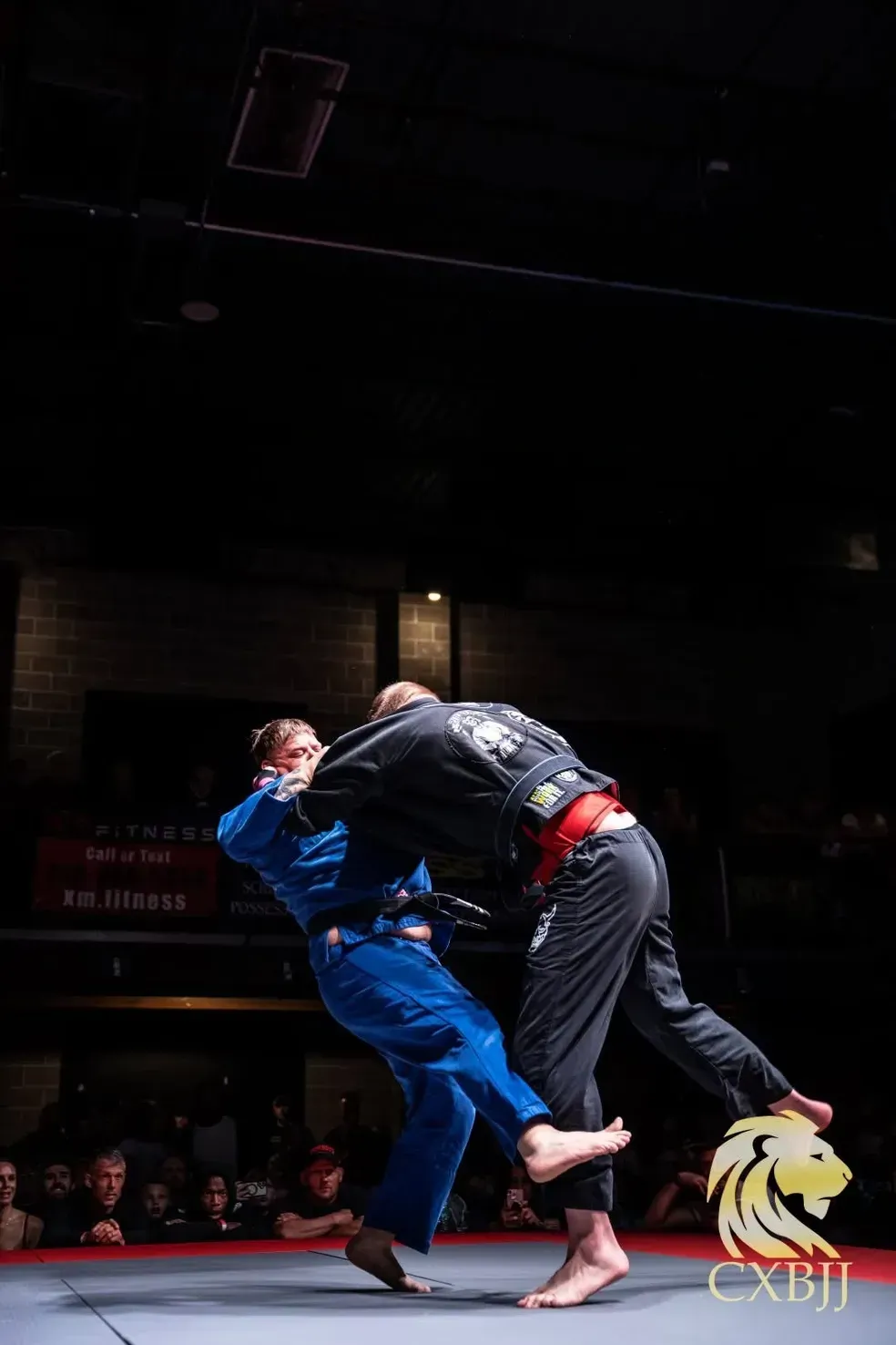 Two martial artists grappling on a mat in Murfreesboro, TN under spotlights in a dark arena