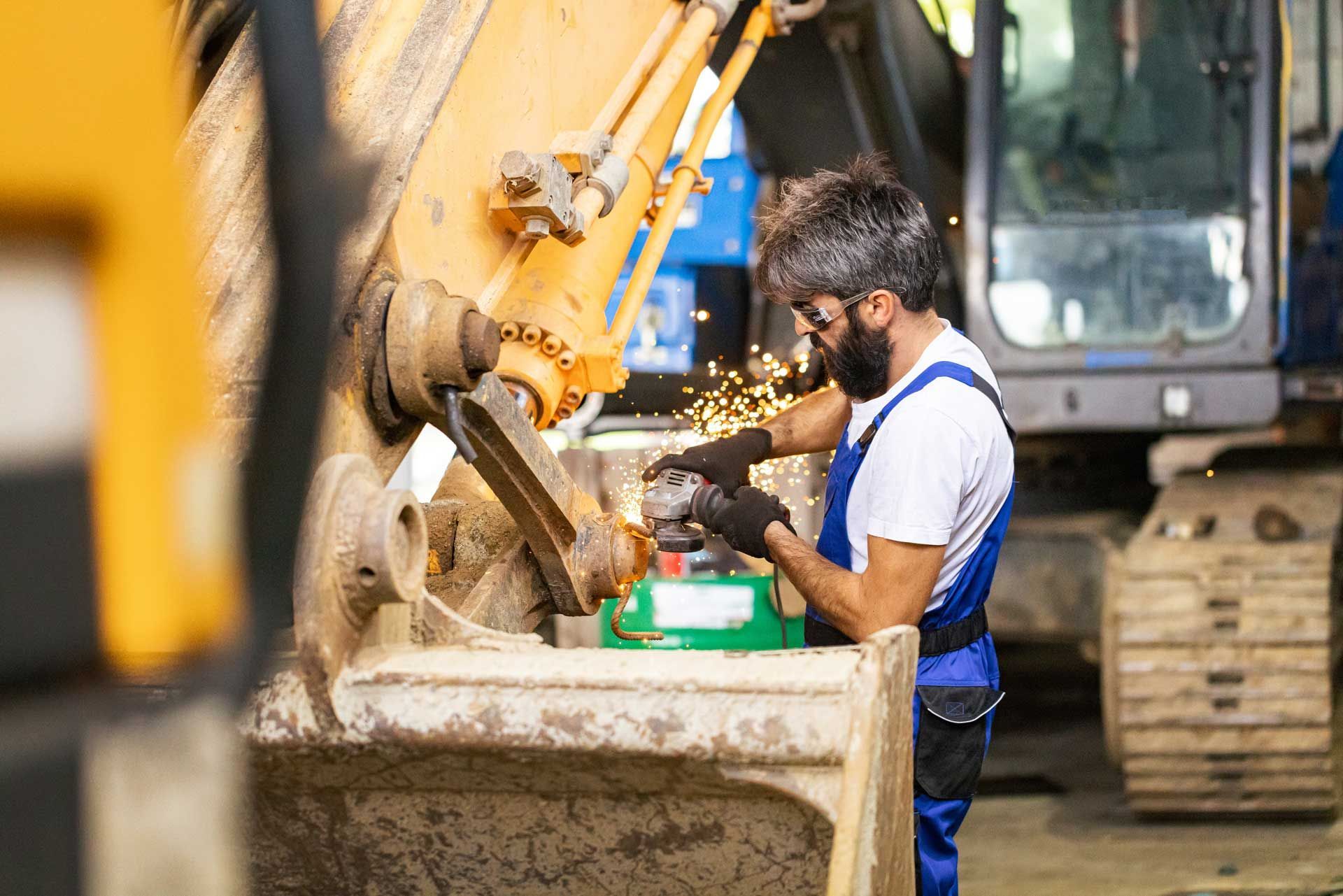 A man is working on an excavator in a garage.