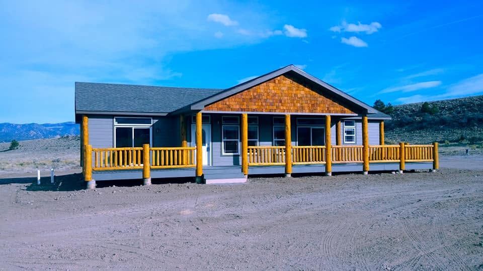 Yellow cabin with blue roof and porch in a barren desert landscape under a clear sky