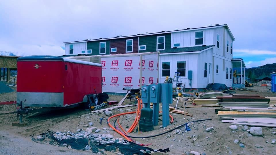 Construction site with a red trailer, white building, and scattered materials under overcast sky