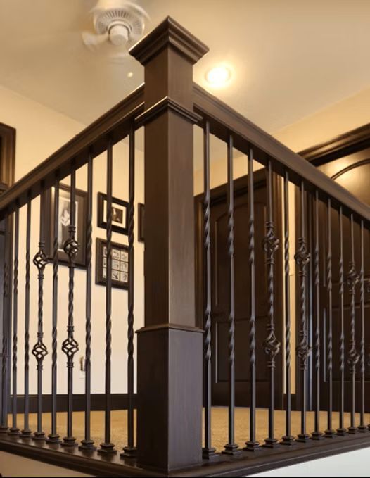 Stairway railing with dark wood posts and black iron balusters in a home interior