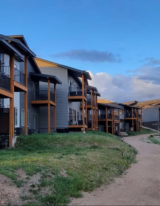 Apartment buildings beside a grassy path at dusk under a blue sky