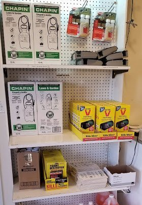 Shelves stocked with lawn and garden supplies: sprayers, traps, and related items in a store setting.