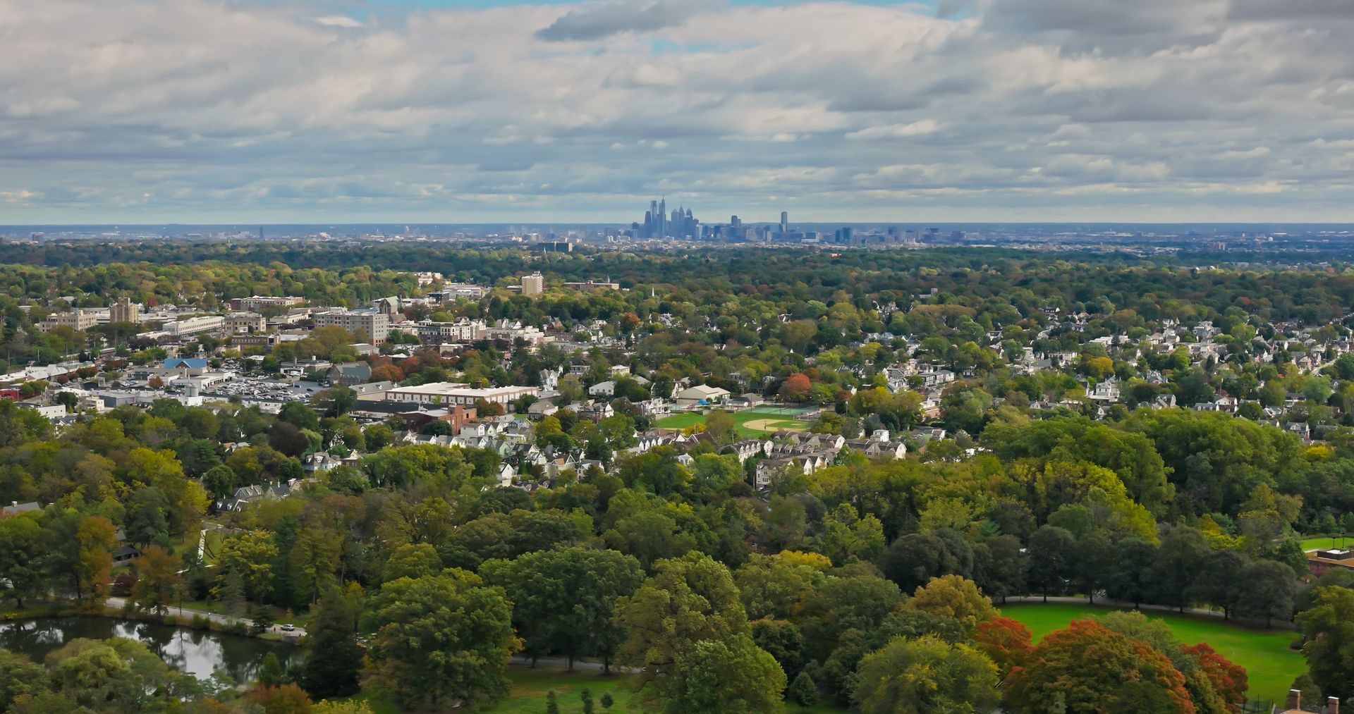 An aerial view of a city with a park in the foreground and a city skyline in the background.
