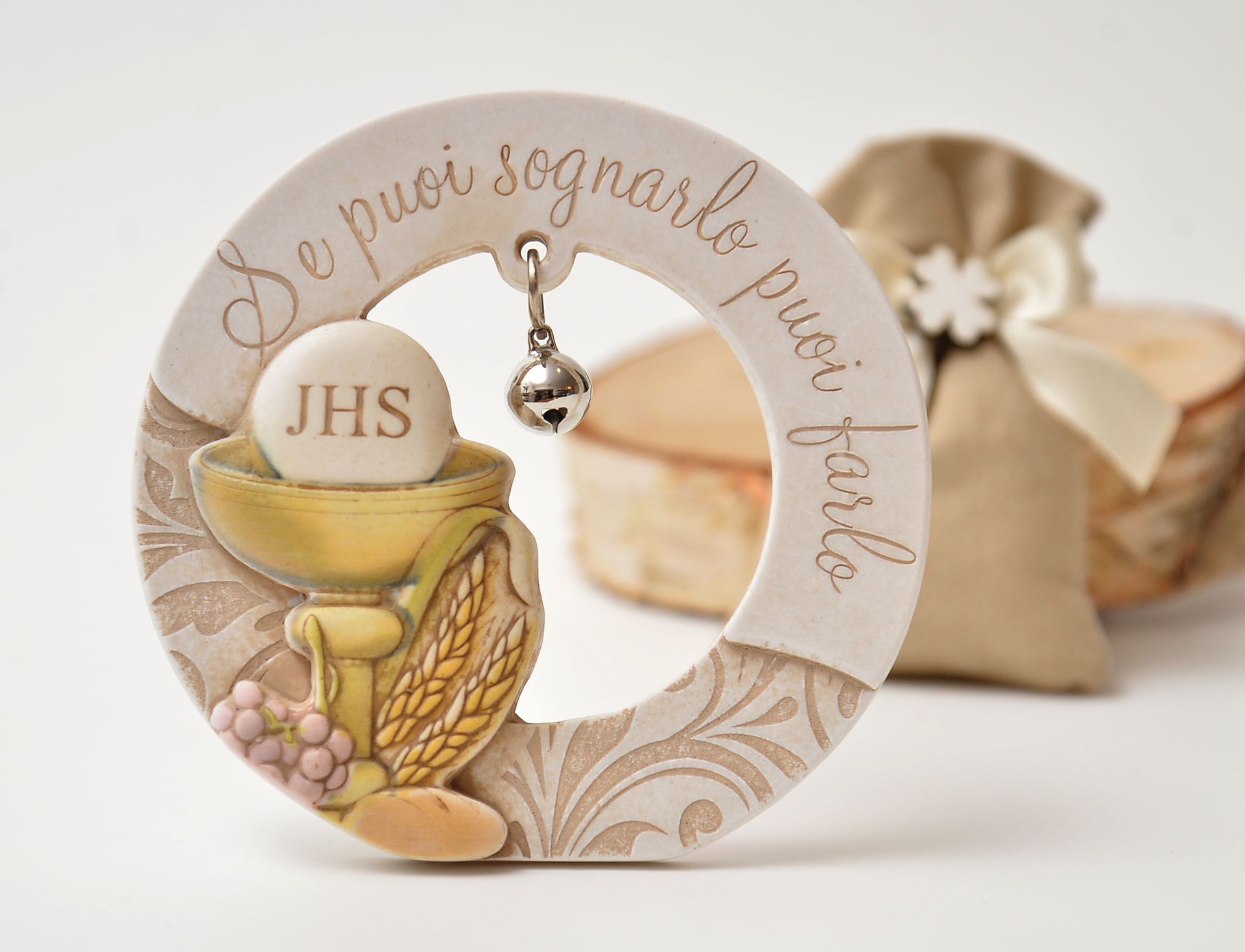 Decorazione in ceramica a tema Comunione con calice, pane e uva. Dal cerchio pende una piccola campanella con la scritta: 