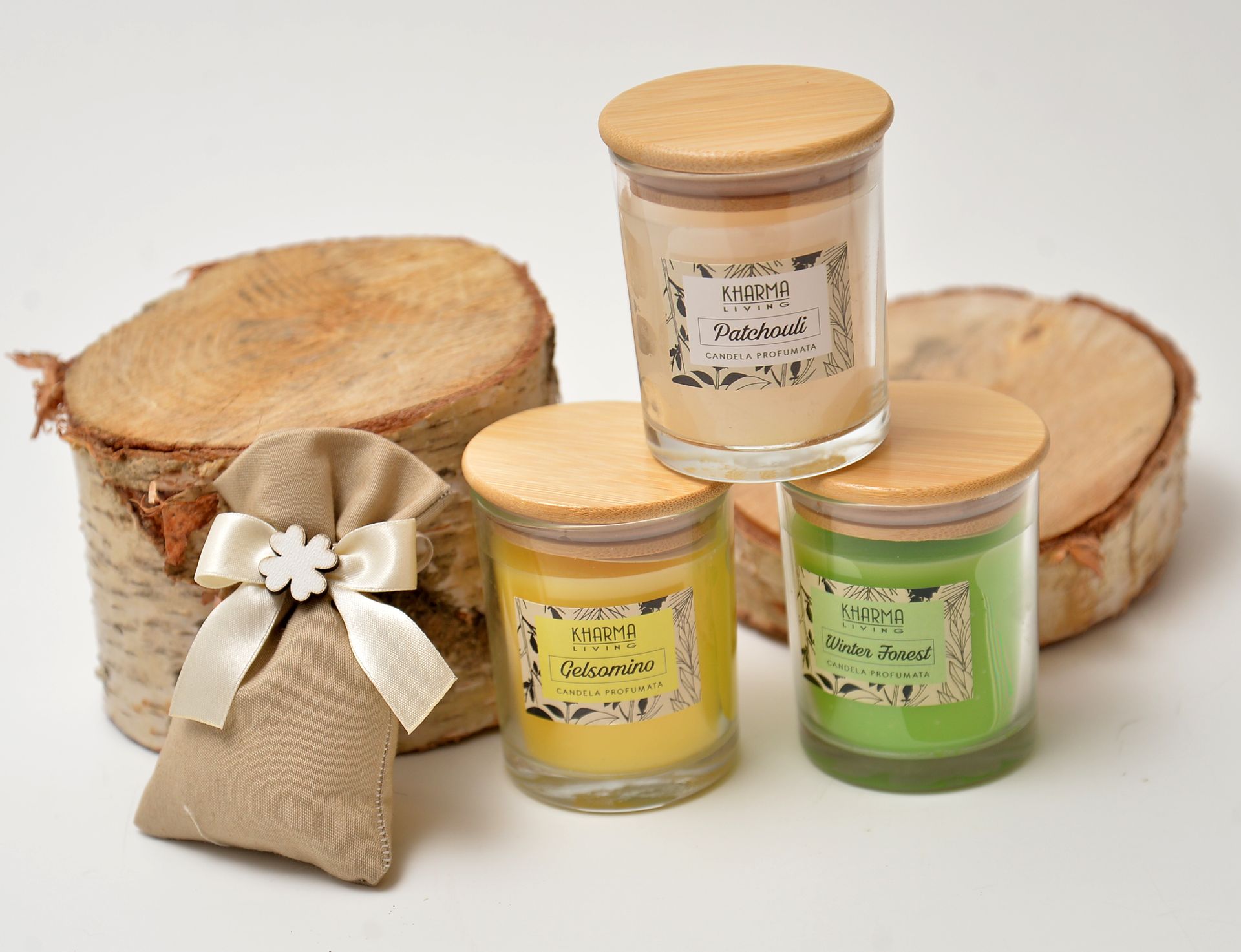 Candele in barattoli di vetro con coperchi ed etichette in legno, piccolo sacchetto di iuta, fette di legno di betulla, sfondo bianco.