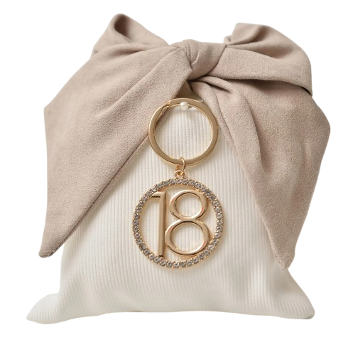 Fiocco in tessuto beige su un cuscino bianco, portachiavi dorato con la scritta