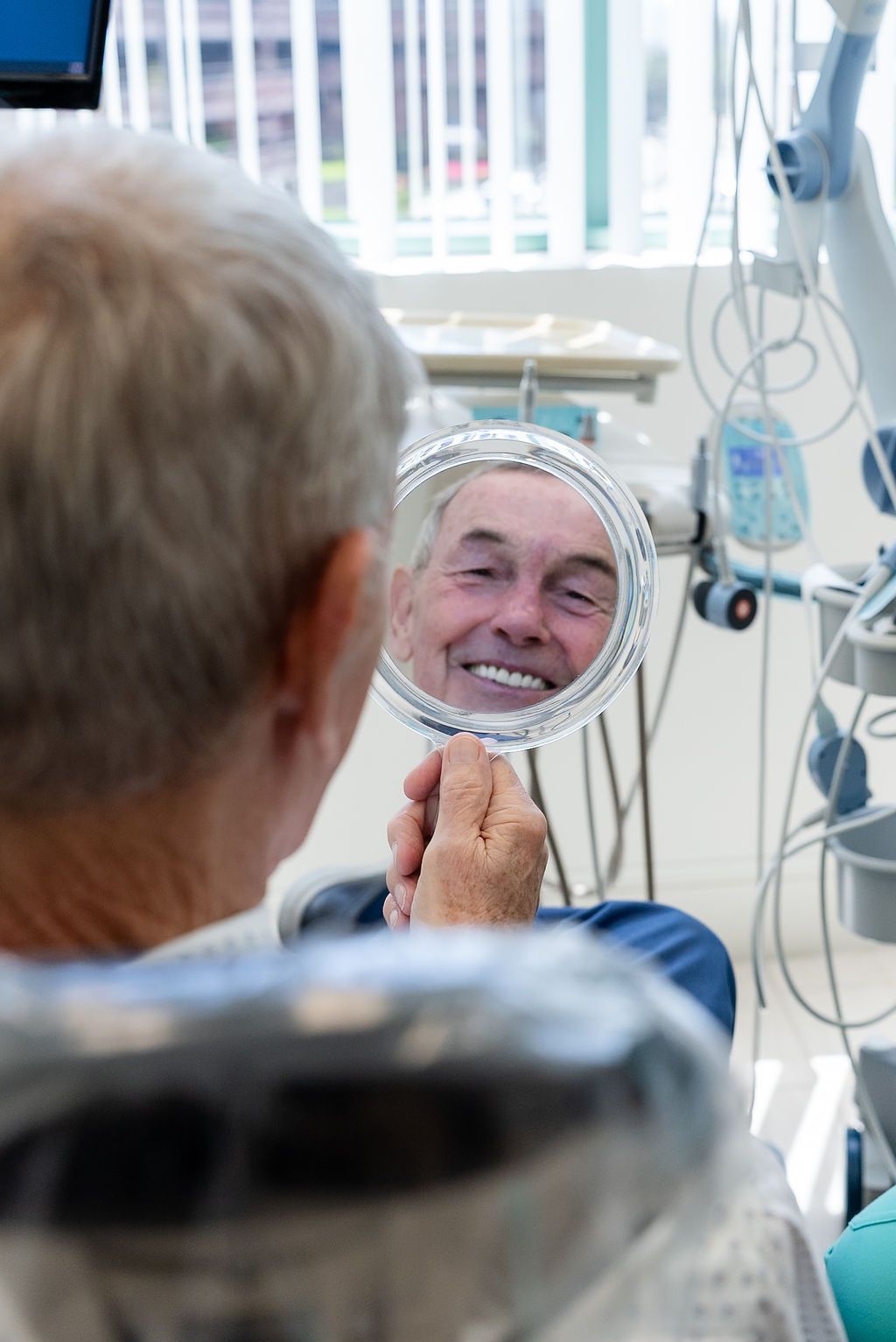 Patient viewing cosmetic dentistry results in a handheld dental mirror