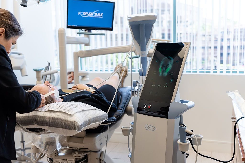 Dental exam room with patient in chair, dentist working, and a monitor beside the equipment.